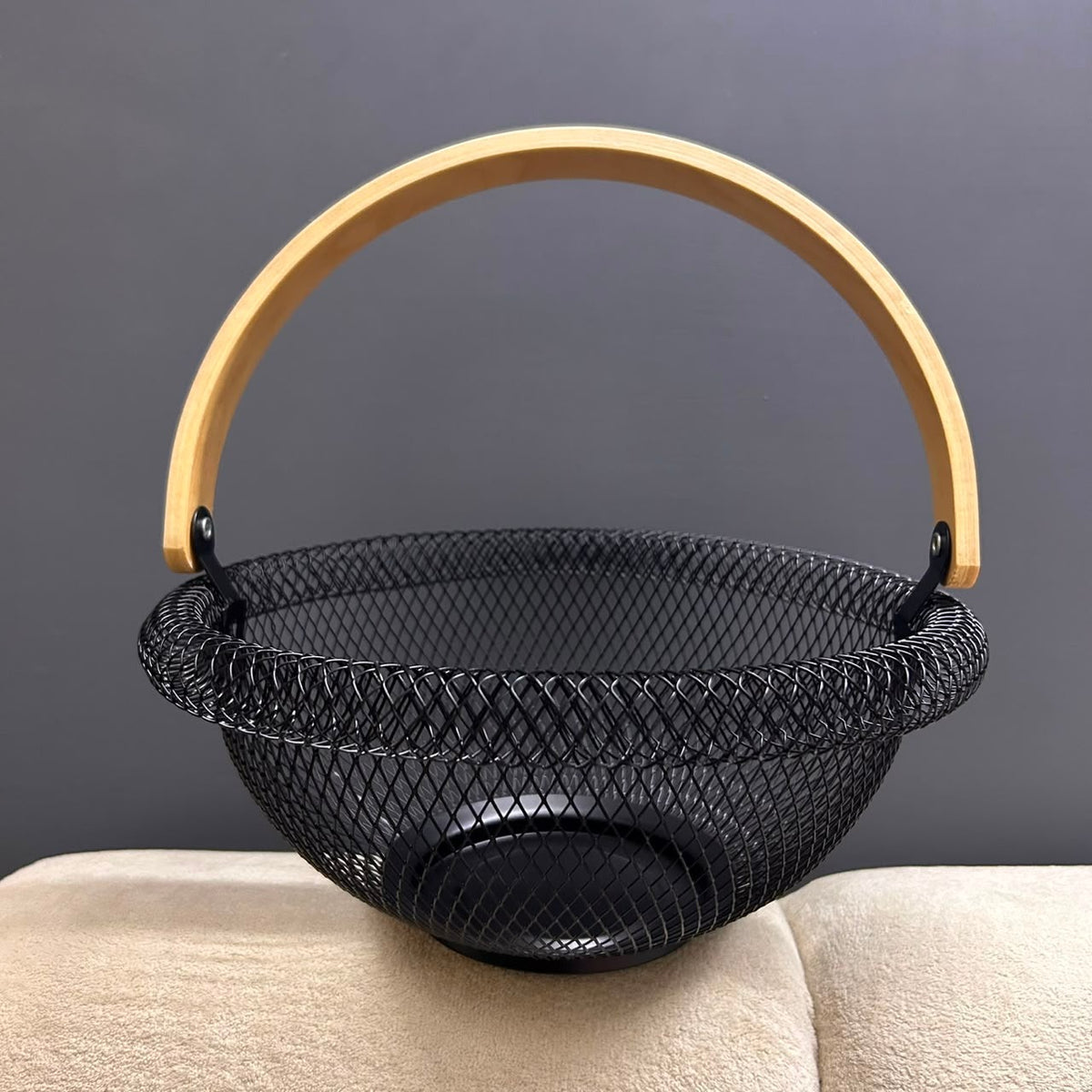 Empty round black wire mesh fruit basket with wooden handle